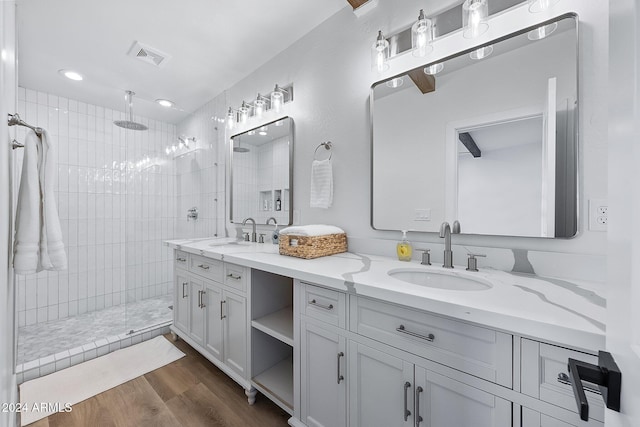 bathroom featuring hardwood / wood-style flooring, vanity, and a tile shower