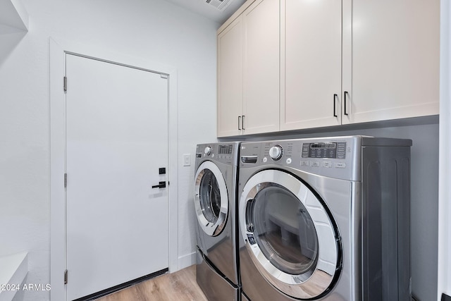 laundry area featuring washer and clothes dryer, cabinets, and light hardwood / wood-style flooring