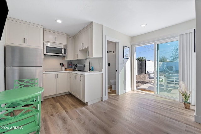 kitchen with white cabinets, light hardwood / wood-style floors, sink, and appliances with stainless steel finishes