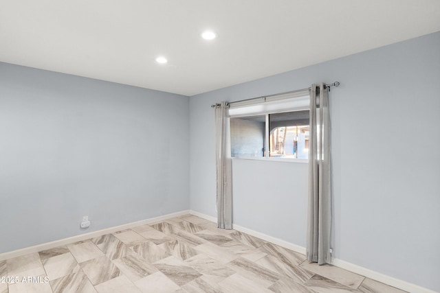 empty room featuring baseboards and recessed lighting