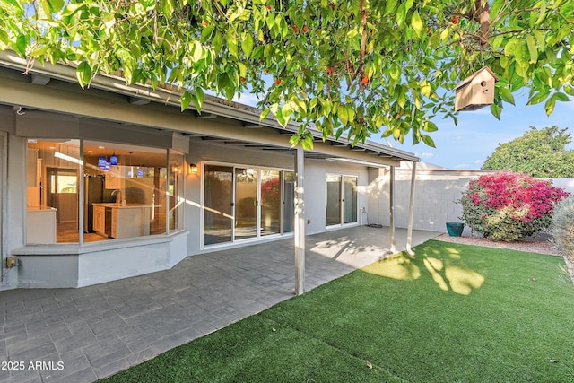 rear view of house with fence, a lawn, and a patio