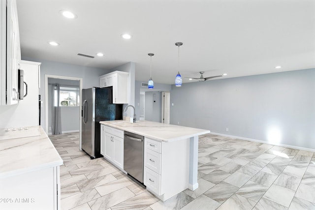 kitchen featuring stainless steel appliances, a sink, white cabinetry, and light stone countertops