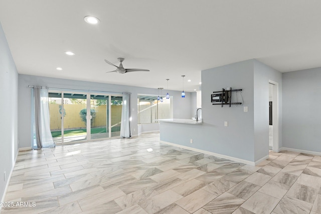 unfurnished living room featuring ceiling fan, baseboards, a sink, and recessed lighting