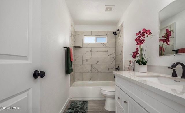 full bathroom with hardwood / wood-style flooring, tiled shower / bath, vanity, and toilet