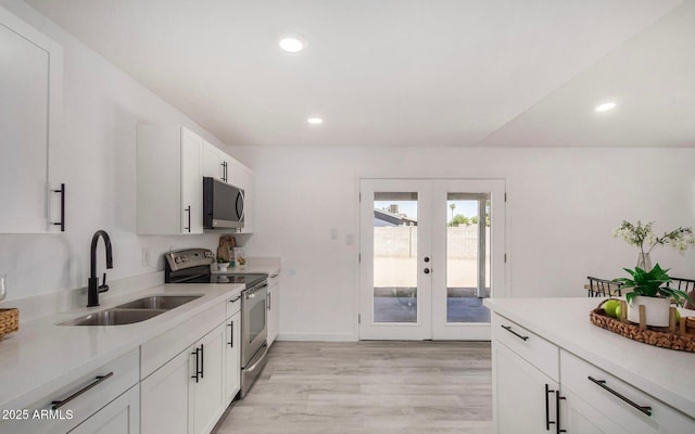 kitchen with white cabinetry, sink, stainless steel appliances, light wood-type flooring, and french doors