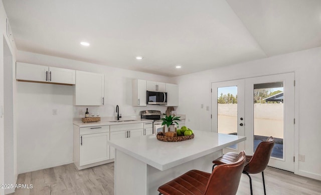 kitchen featuring french doors, sink, white cabinets, stainless steel appliances, and light hardwood / wood-style flooring