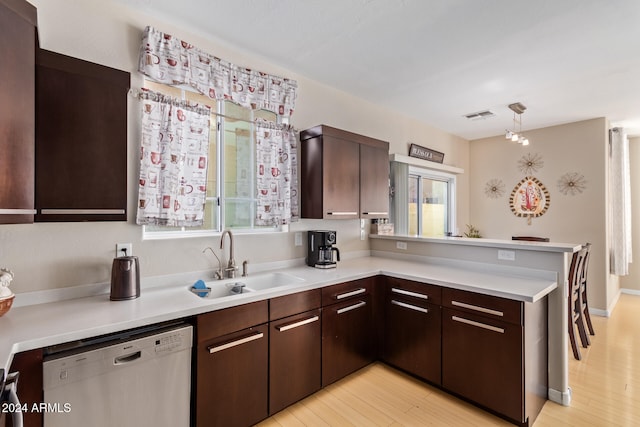 kitchen featuring dishwasher, sink, light wood-type flooring, and hanging light fixtures