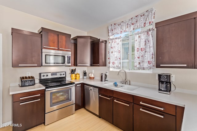 kitchen featuring sink, light wood-type flooring, stainless steel appliances, and dark brown cabinetry