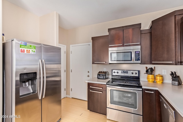 kitchen with dark brown cabinets, stainless steel appliances, and light wood-type flooring