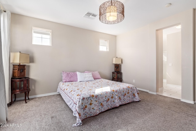 carpeted bedroom with ensuite bath and multiple windows