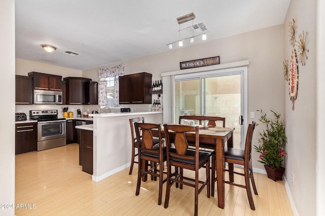 kitchen with sink, dark brown cabinetry, light wood-type flooring, appliances with stainless steel finishes, and kitchen peninsula