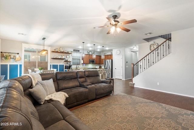 living area with dark wood-type flooring, stairway, a ceiling fan, and visible vents