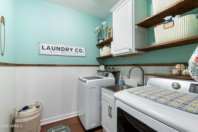 clothes washing area with cabinet space, dark wood-style flooring, a sink, wainscoting, and washer and clothes dryer