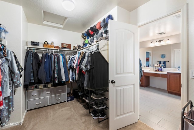 spacious closet featuring attic access, visible vents, and built in desk