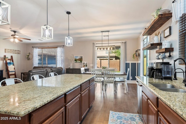 kitchen with open shelves, a sink, dark wood-type flooring, pendant lighting, and stainless steel dishwasher