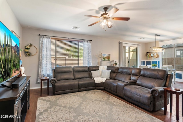 living area with visible vents, baseboards, wood finished floors, and a ceiling fan