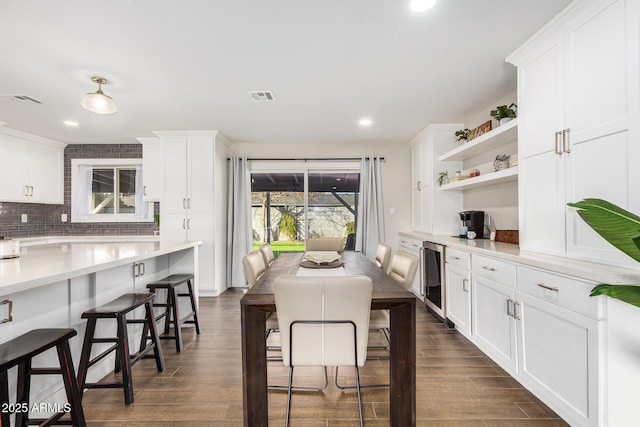 kitchen with white cabinetry, dark hardwood / wood-style floors, beverage cooler, and a breakfast bar