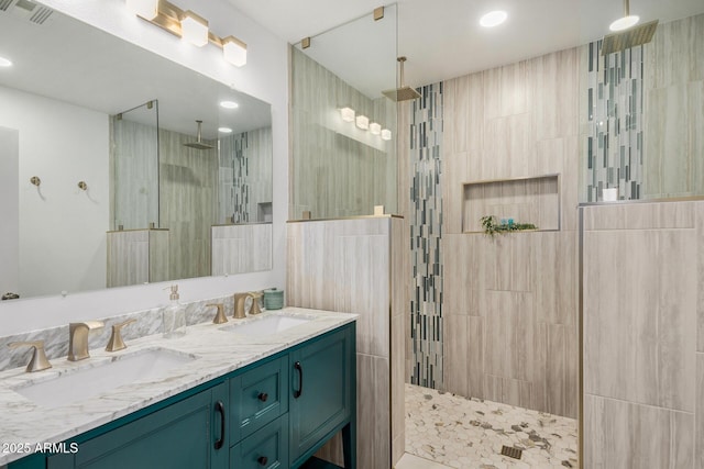 bathroom with a tile shower and vanity