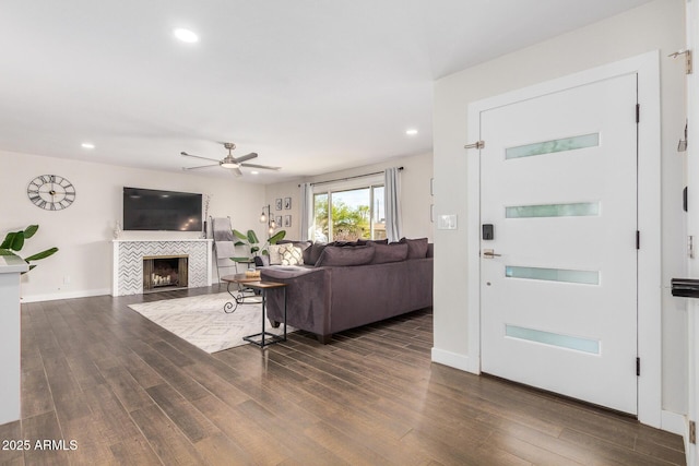 living room with a tile fireplace, dark hardwood / wood-style floors, and ceiling fan