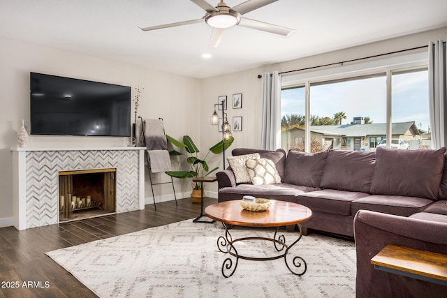 living room with a tile fireplace, dark hardwood / wood-style floors, and ceiling fan