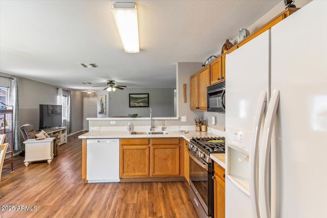 1057 E Silversmith Trl, San Tan Valley, AZ 85143 - kitchen with white appliances, a peninsula, brown cabinetry, open floor plan, and light countertops