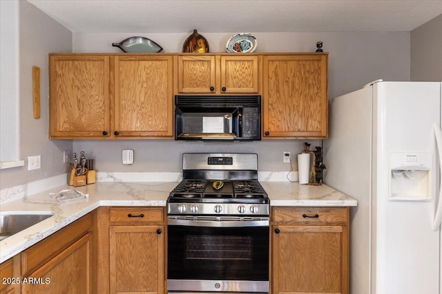 1057 E Silversmith Trl, San Tan Valley, AZ 85143 - kitchen featuring white refrigerator with ice dispenser, black microwave, stainless steel gas range oven, light stone counters, and brown cabinetry