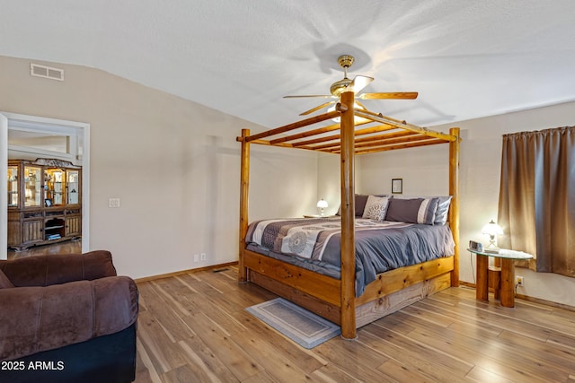 bedroom featuring baseboards, visible vents, lofted ceiling, ceiling fan, and wood finished floors