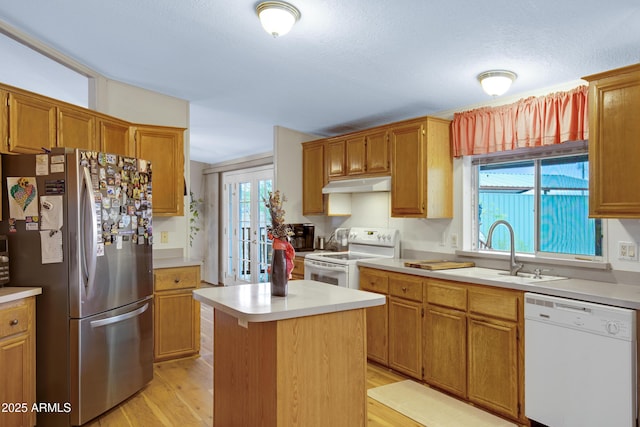 kitchen featuring white appliances, under cabinet range hood, light countertops, and a sink