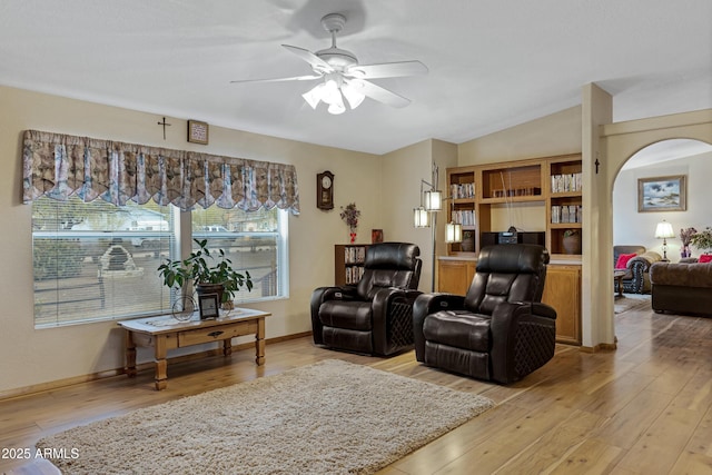 living room with lofted ceiling, arched walkways, and light wood-style flooring