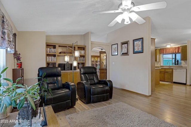 living area featuring vaulted ceiling, ceiling fan, light wood finished floors, and arched walkways