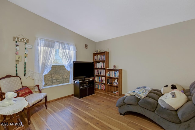 living area with light wood-style floors, baseboards, and vaulted ceiling