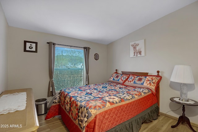 bedroom featuring vaulted ceiling, baseboards, and wood finished floors