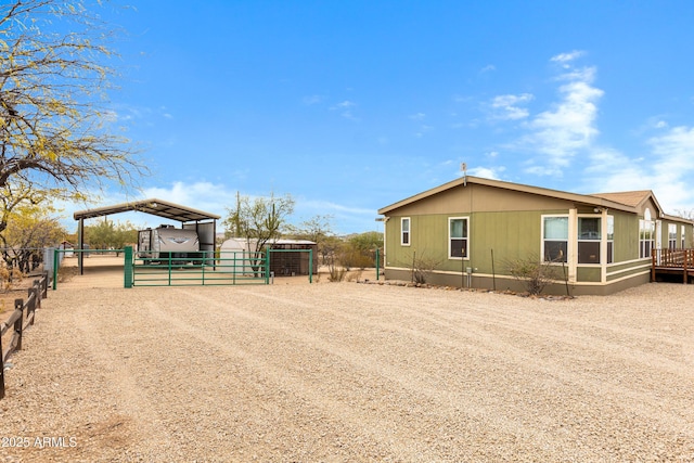 view of side of home with an outbuilding, a carport, an exterior structure, and fence