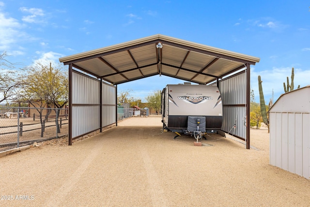 view of car parking featuring dirt driveway, fence, and a detached carport