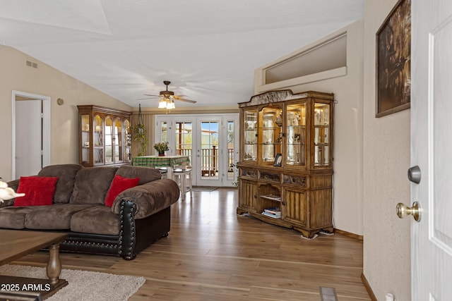 living area featuring vaulted ceiling, french doors, wood finished floors, and visible vents