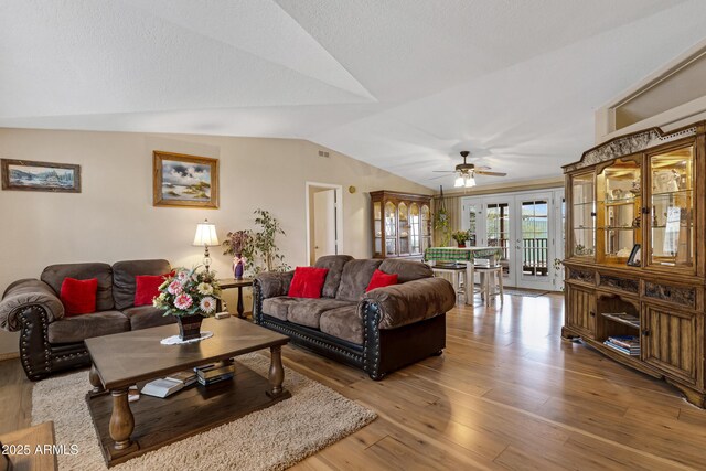 living area featuring lofted ceiling, ceiling fan, visible vents, and wood finished floors