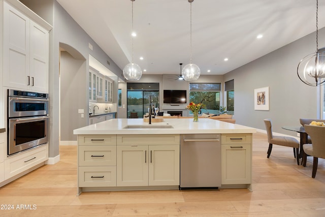 kitchen featuring a center island with sink, stainless steel appliances, pendant lighting, sink, and light hardwood / wood-style floors