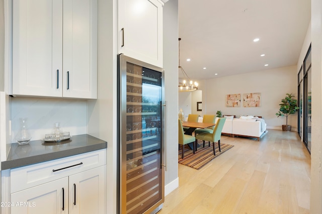 kitchen featuring white cabinetry, light hardwood / wood-style floors, decorative light fixtures, and beverage cooler