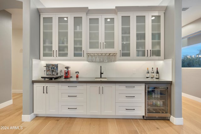 bar with light hardwood / wood-style floors, white cabinetry, wine cooler, and sink