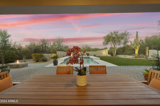 patio terrace at dusk with a yard and an outdoor fire pit