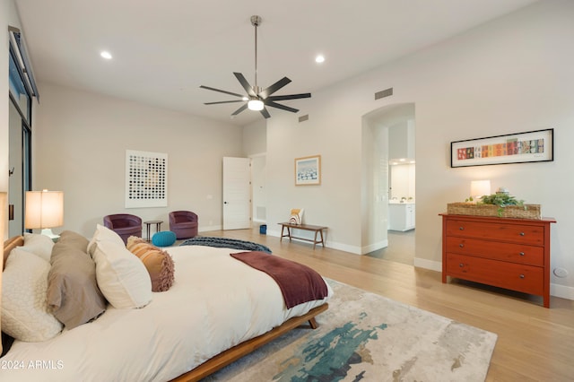 bedroom with light wood-type flooring, ceiling fan, and connected bathroom