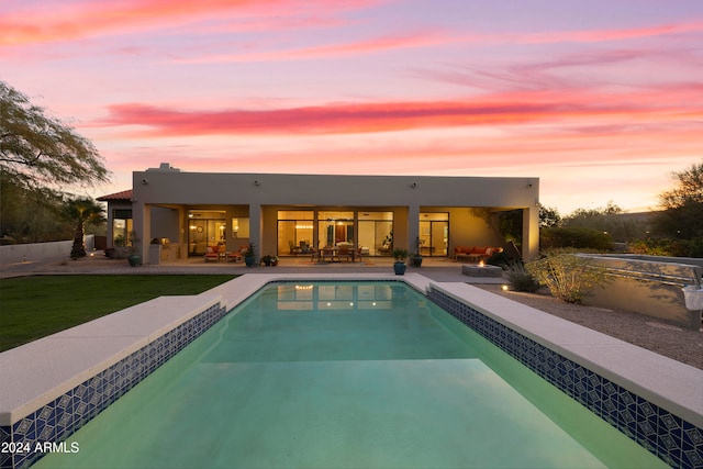 pool at dusk with a patio area