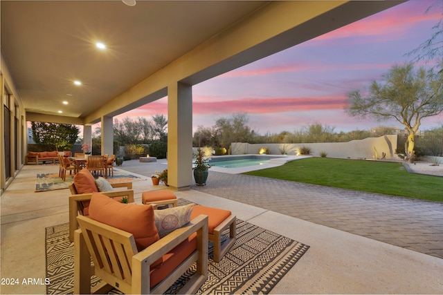 patio terrace at dusk with outdoor lounge area, a fenced in pool, and a yard