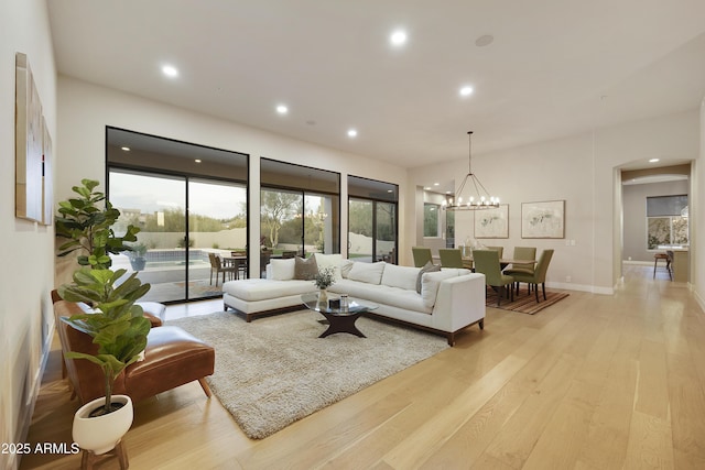 living room featuring arched walkways, light wood-style floors, a wealth of natural light, and recessed lighting