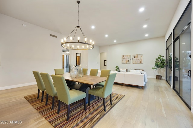dining area with light wood-type flooring, baseboards, visible vents, and a notable chandelier