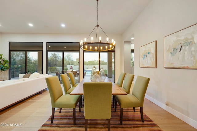 dining space with light hardwood / wood-style floors and a notable chandelier