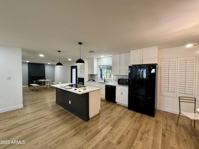 kitchen featuring black appliances, white cabinetry, a sink, a kitchen island with sink, and recessed lighting