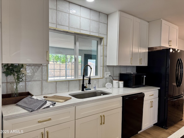 kitchen with black appliances, a sink, white cabinetry, light stone counters, and backsplash