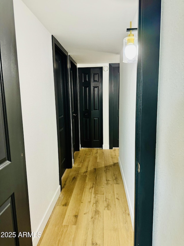 corridor featuring light wood-style flooring and baseboards