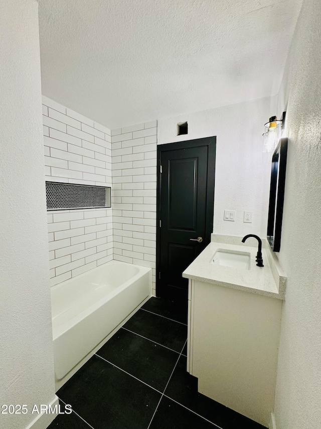 bathroom with tile patterned floors, vanity, a textured wall, and a textured ceiling